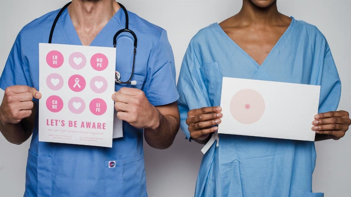 Two healthcare workers holding breast cancer awareness posters promoting early detection and education.