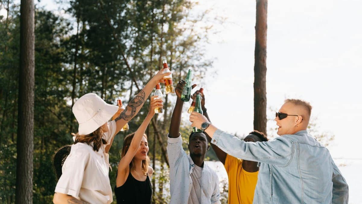 A diverse group of friends enjoying a sunny day by toasting with beverages outdoors.