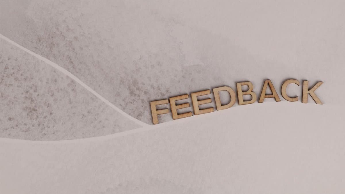 Wooden letters spelling 'FEEDBACK' arranged on textured paper background, conveying a conceptual theme.