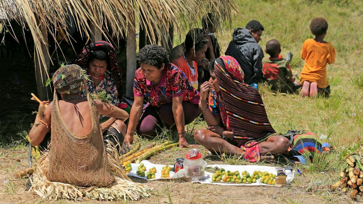 Group of people sharing fruit in a rural outdoor market setting, a cultural exchange of tradition.