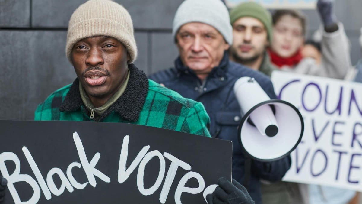 Diverse group of activists marching for voting rights with placards and a megaphone.