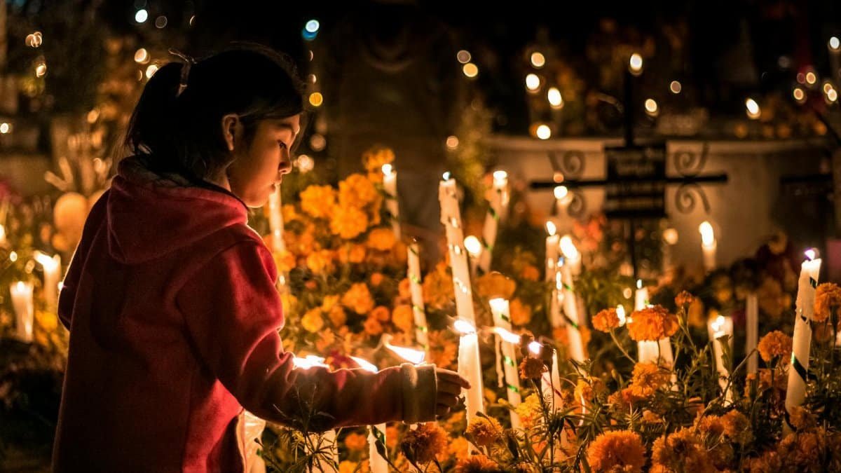 A young girl lighting candles at a Día de los Muertos cemetery in Oaxaca.