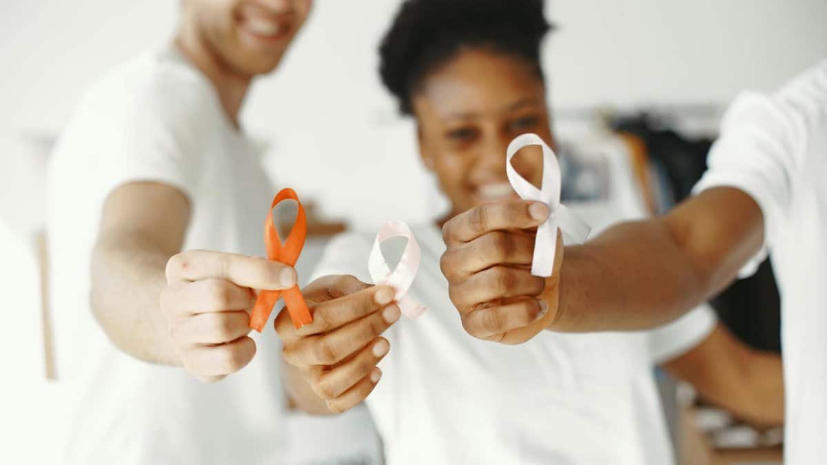 Diverse group holding health awareness ribbons, showing unity and support.