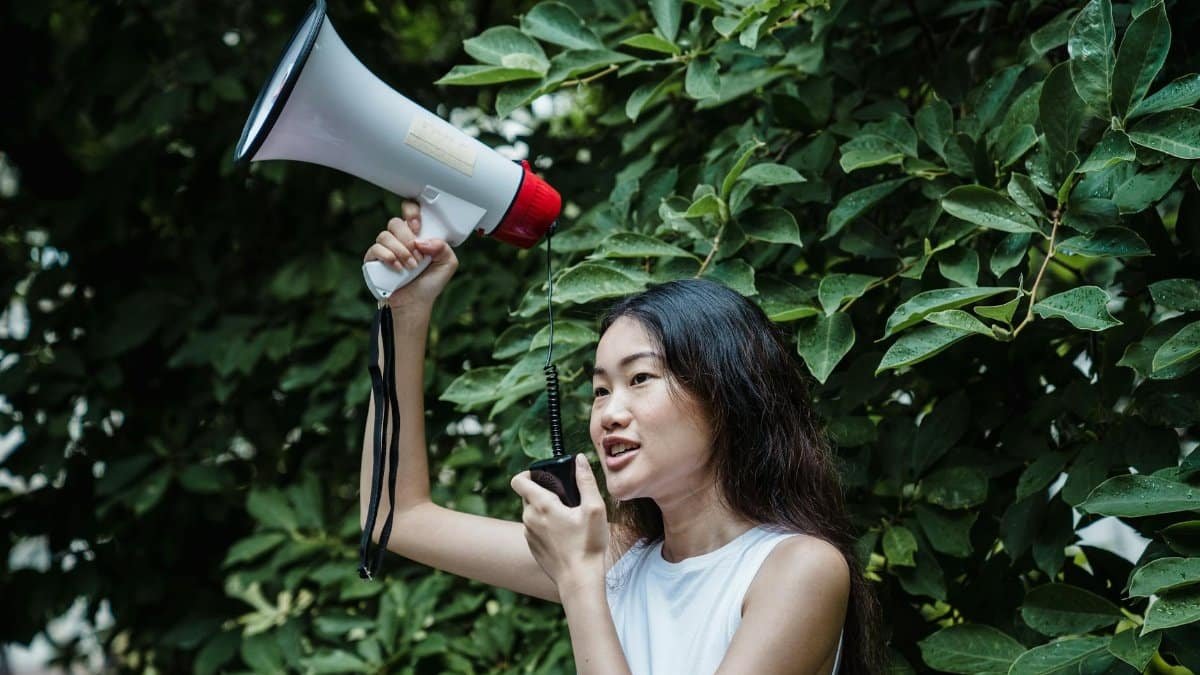 Confident young woman with megaphone at an outdoor rally, advocating for change.