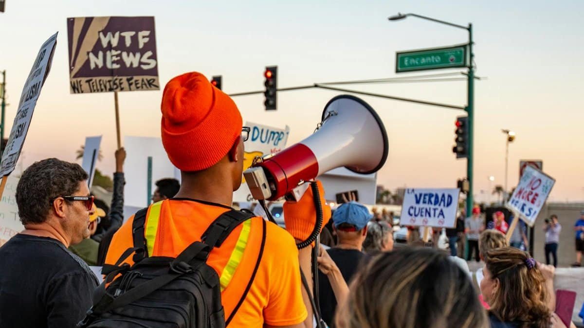 Colorful street protest with people holding signs and a megaphone, emphasizing diverse voices.