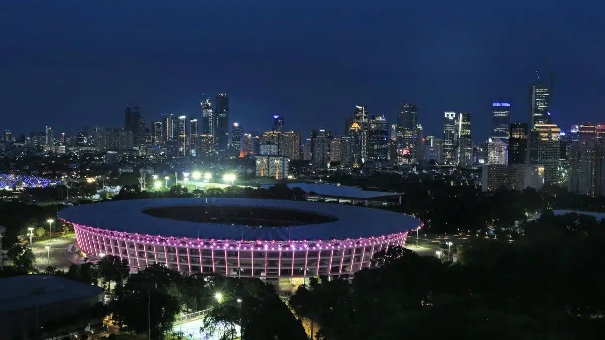 A stunning nighttime skyline view of Jakarta with illuminated Gelora Bung Karno Stadium in the foreground.