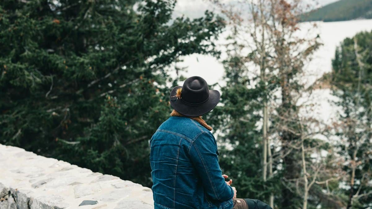 A man in a hat enjoys a serene view in Banff National Park, Canada.