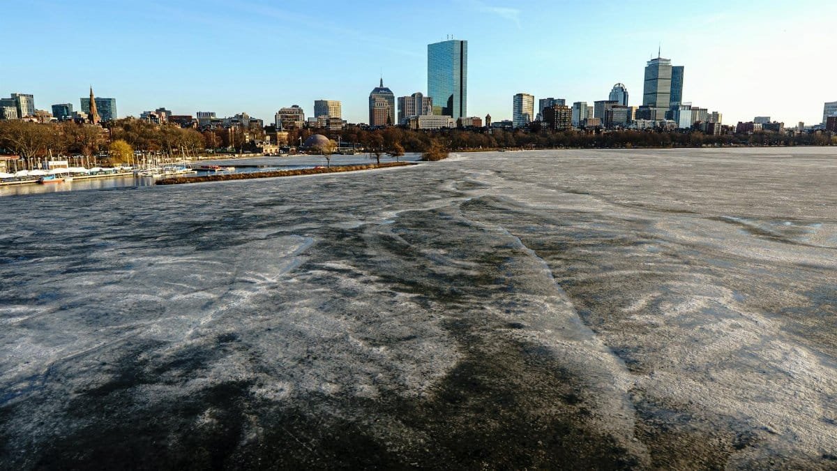 Stunning view of Boston's skyline with the icy Charles River in the foreground on a clear winter day.