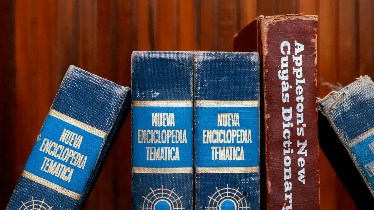 Close-up of old encyclopedias and a dictionary on a wooden shelf, showcasing vintage charm.