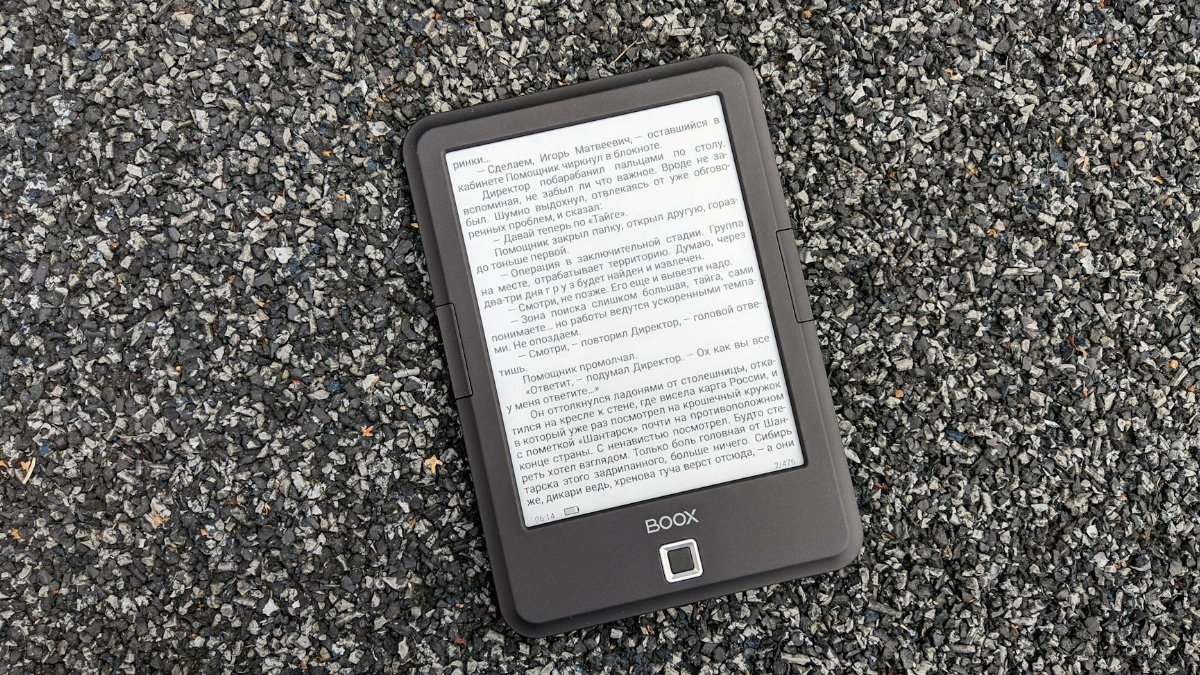 Digital BOOX e-book reader placed on a textured gravel surface, offering a tech contrast.