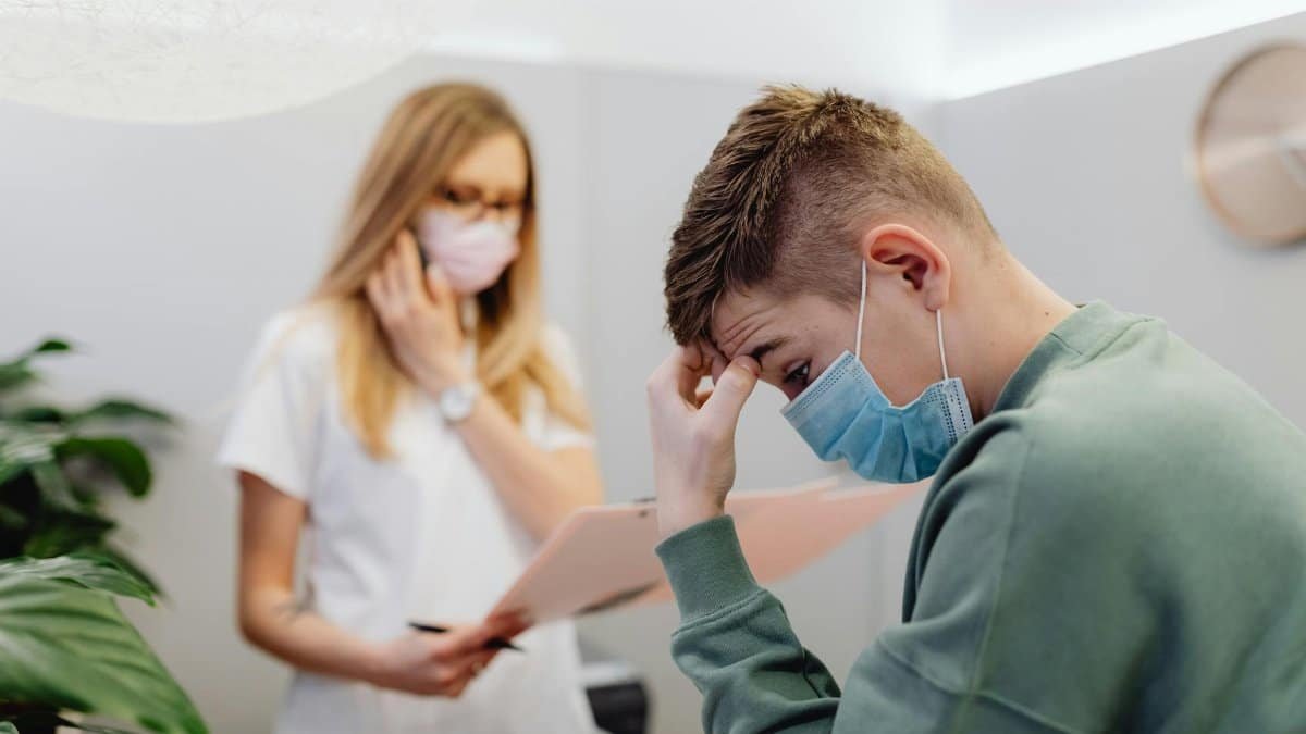 A worried patient discusses with a healthcare professional in a medical office setting.