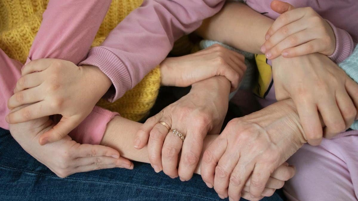 Multiple arms intertwined, symbolizing family unity and support across generations.
