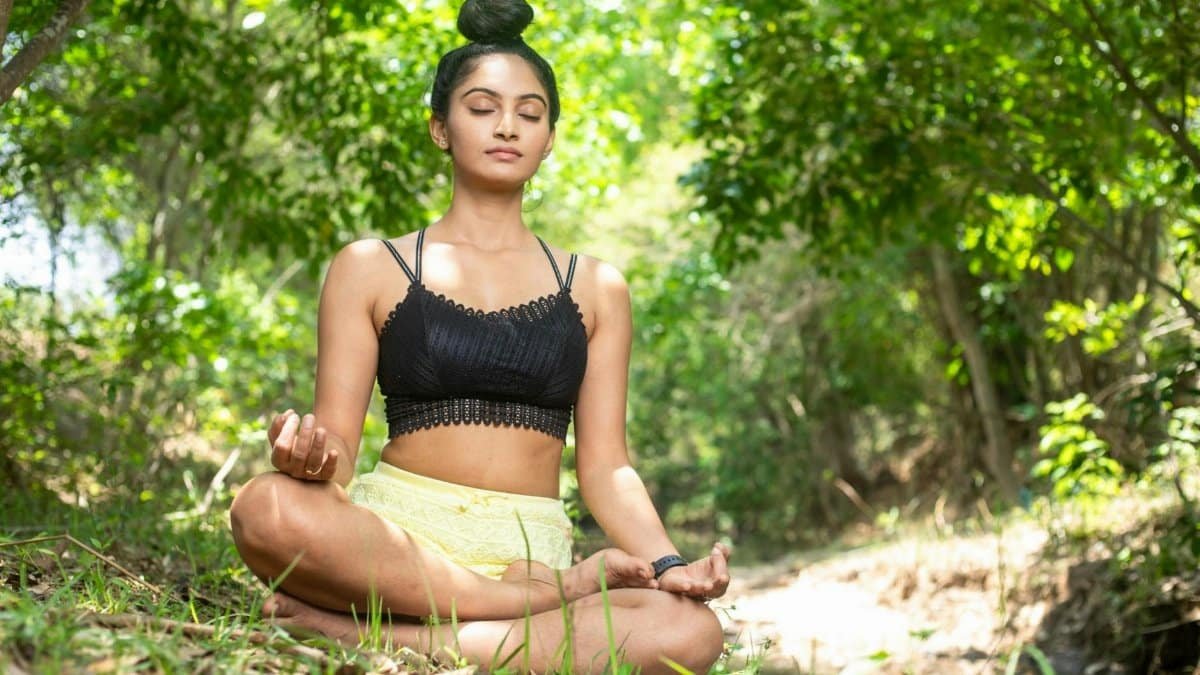 A woman meditating in a serene forest setting, embodying tranquility and mindfulness.