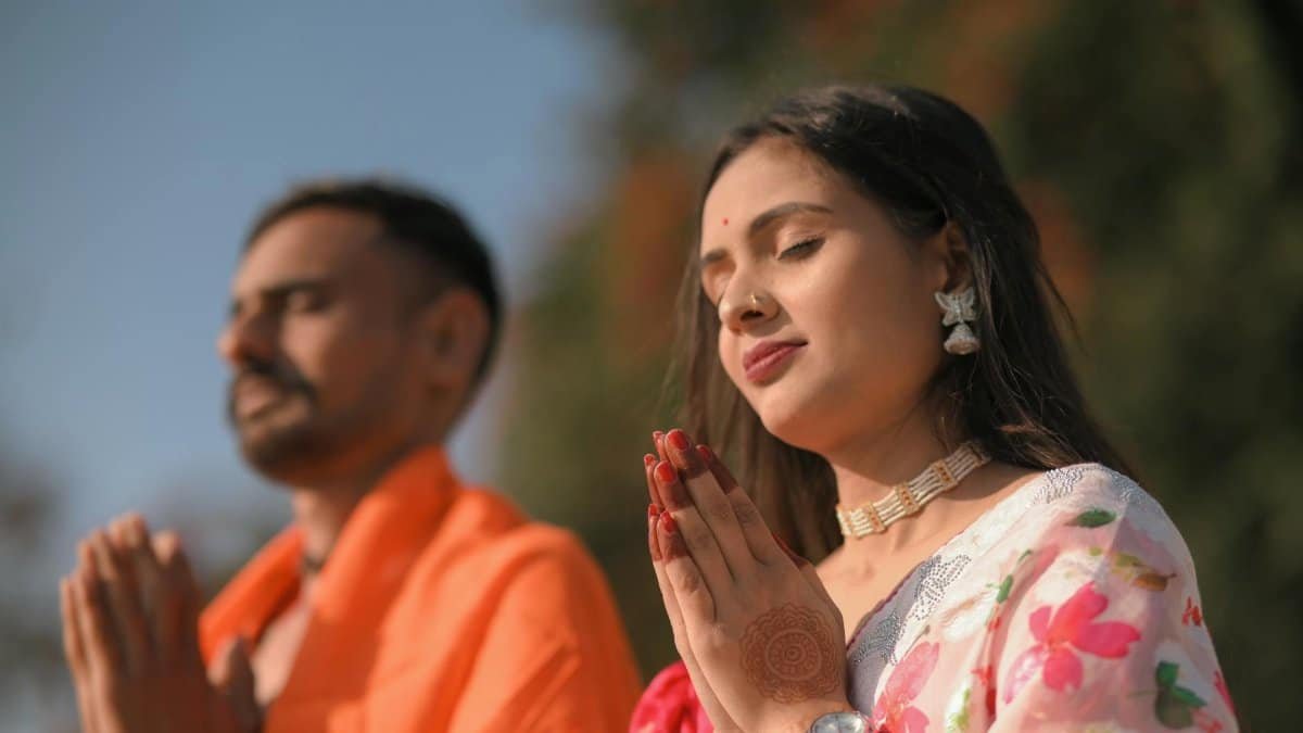 A serene couple practicing meditation outdoors, embracing traditional Indian attire and spirituality.