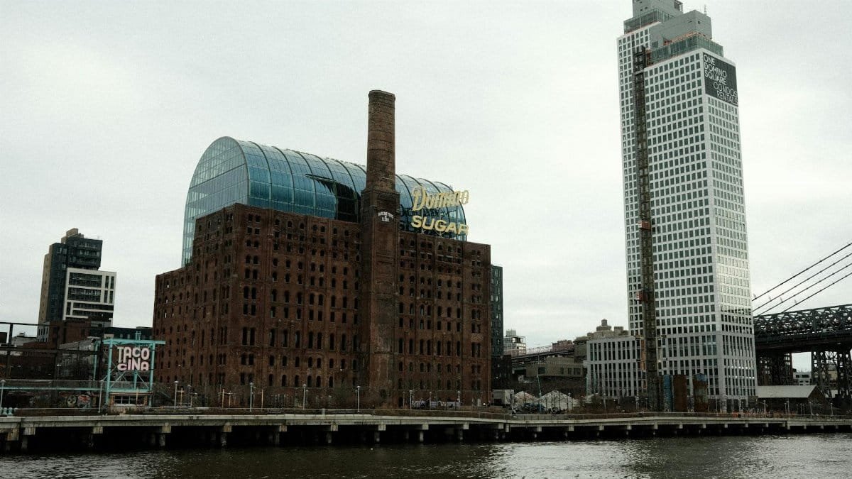 Historical Domino Sugar Refinery by the riverfront in Brooklyn with modern skyscrapers, NYC.