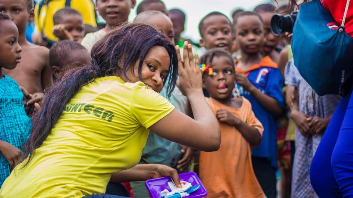 A vibrant scene of children and volunteers participating in an outdoor community outreach activity.