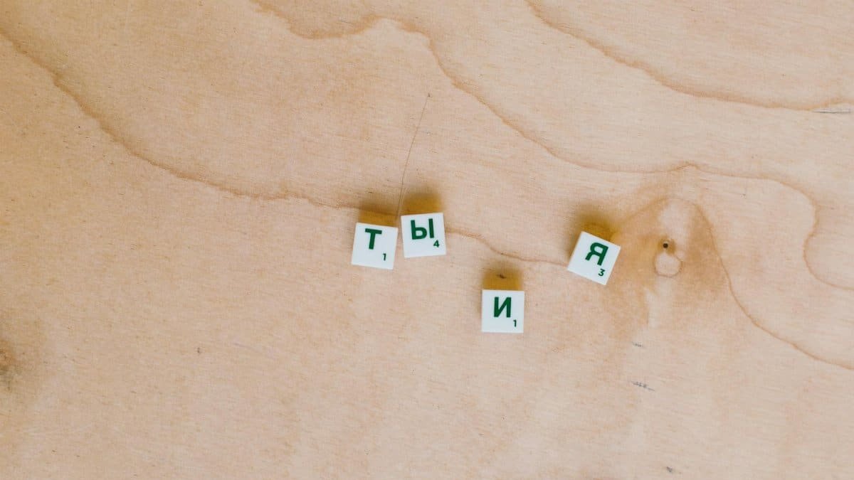 Cyrillic Scrabble tiles arranged on a wooden surface showcasing Russian text.