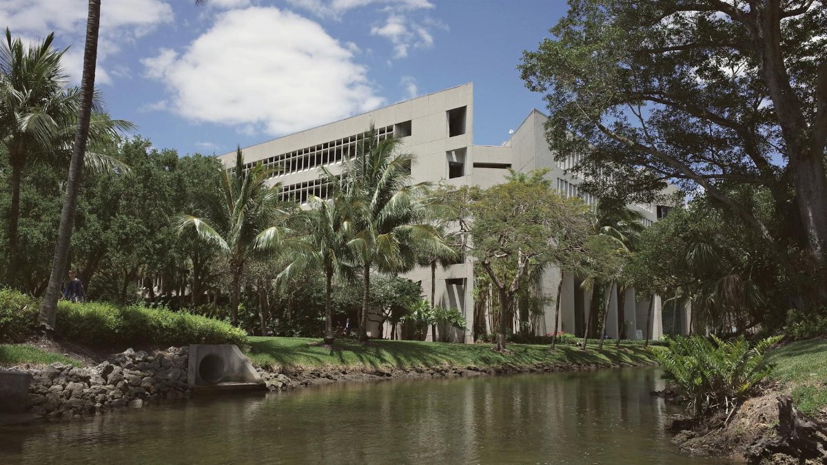 Serene view of a university campus in Coral Gables, Florida with lush greenery and waterway.