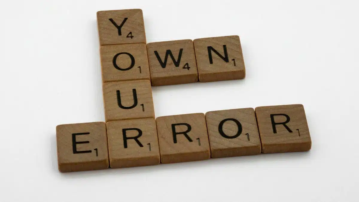 Scrabble tiles spelling 'Own Your Error' on a white background.