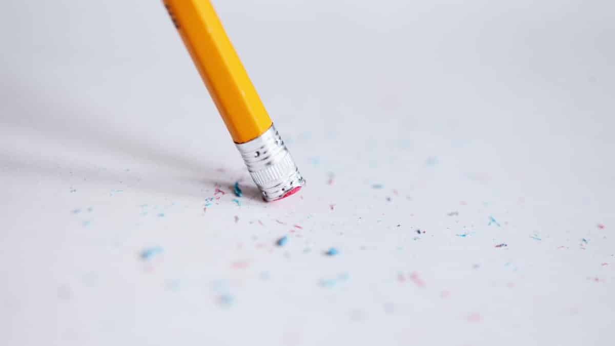 Macro shot of a yellow pencil erasing on paper with eraser shavings.
