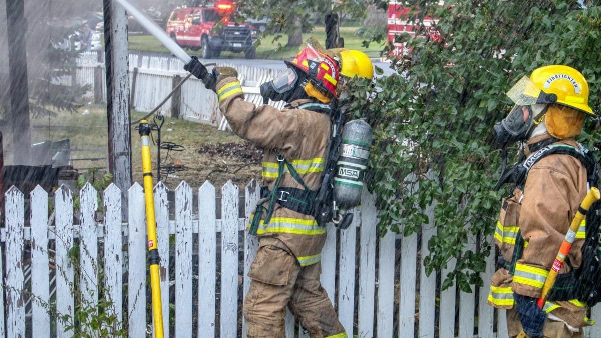 Firefighters in protective gear extinguish a fire in Chewelah, WA, showcasing teamwork and bravery.