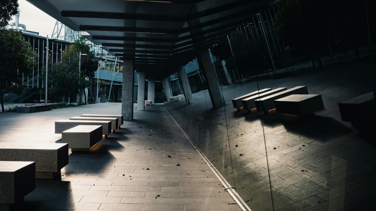 Outdoor walkway with modern benches and reflective windows at dusk.
