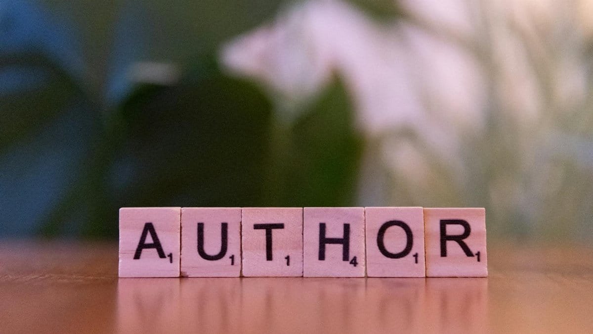 Scrabble tiles forming the word 'Author' on a wooden table, creativity concept.