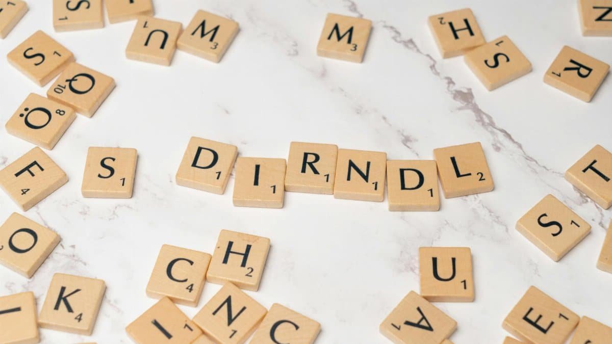 Scrabble tiles spell 'Dirndl' on a marble surface, showcasing cultural heritage.
