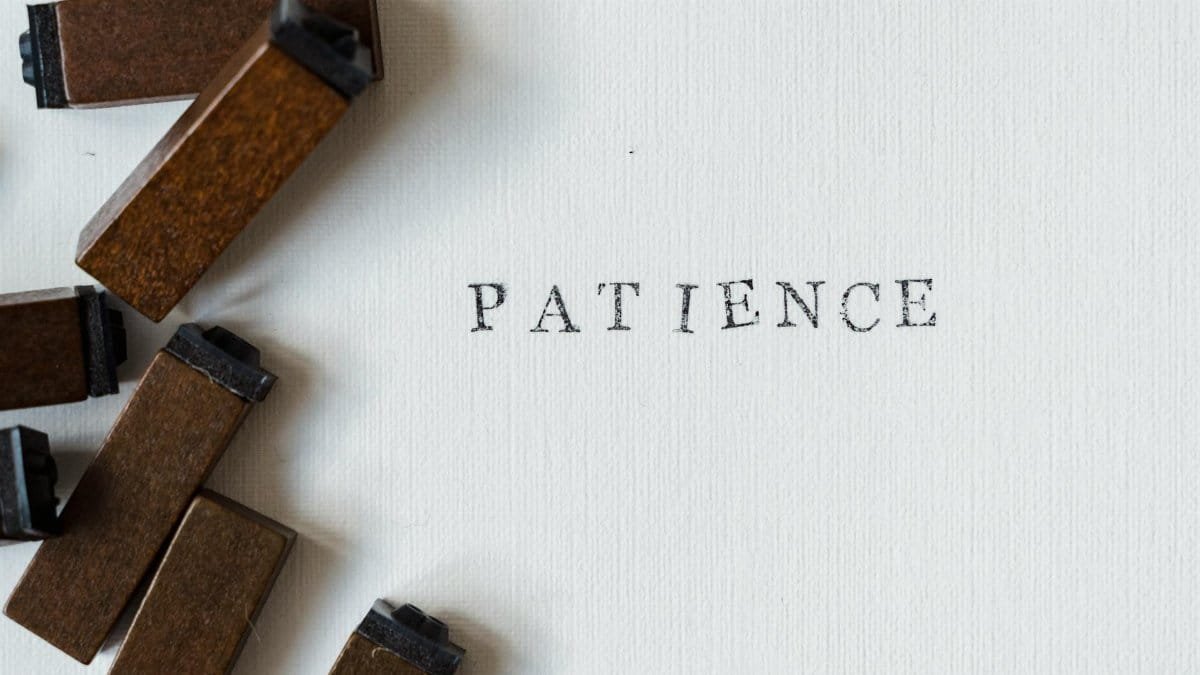 Letterpress 'Patience' on white surface with wooden blocks for a vintage feel.