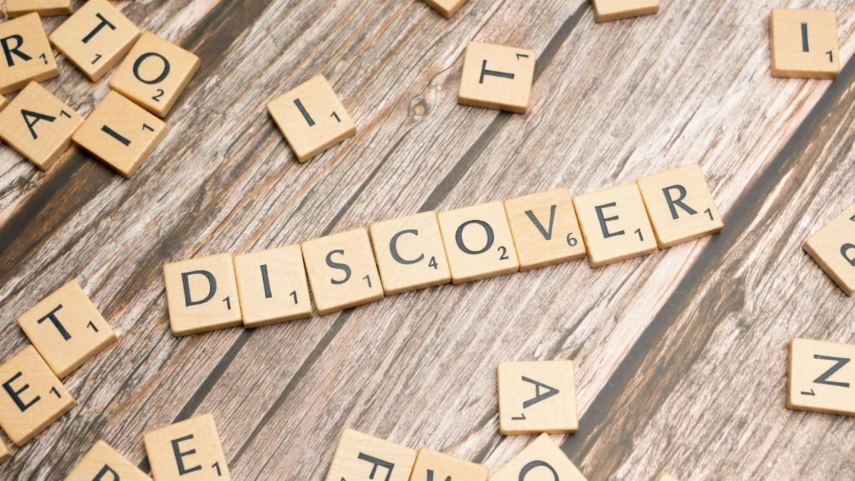 Wooden tiles spelling 'DISCOVER' arranged neatly on a rustic surface.