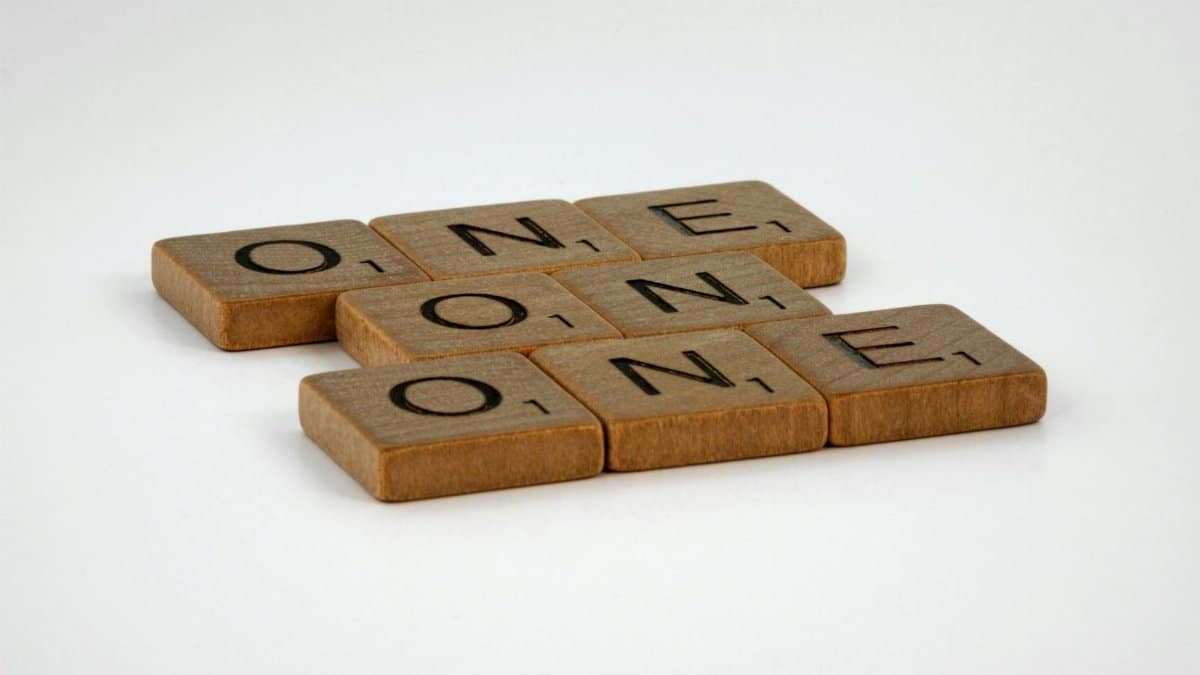 Scrabble tiles spelling 'ONE' arranged in an overlapping pattern on a plain background.