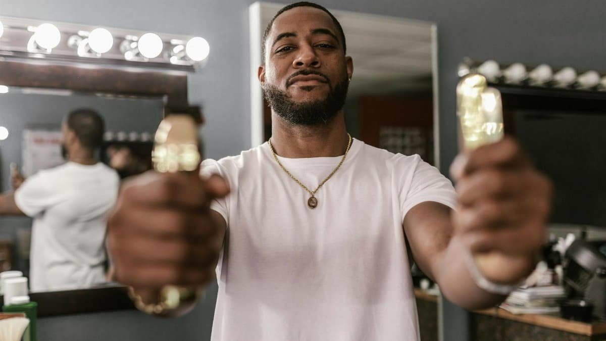 Confident man holding clippers in a barbershop, ready for grooming session.