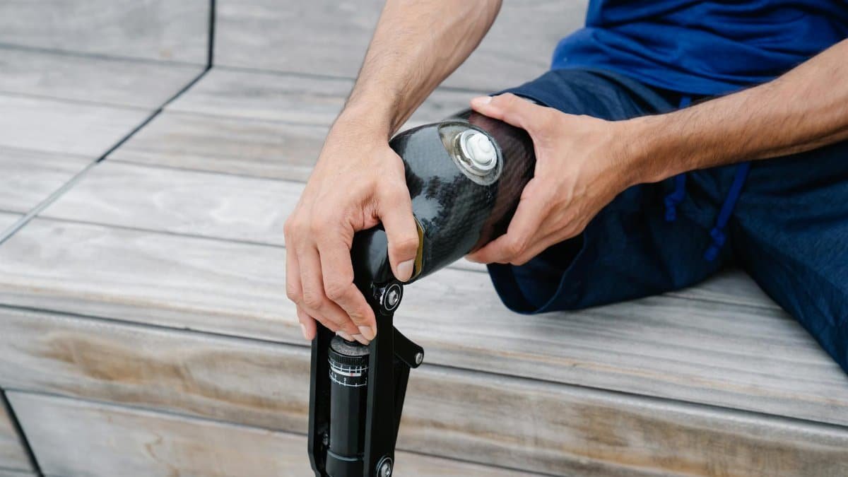 An adult adjusting their prosthetic leg outdoors, highlighting body positivity and disability representation.