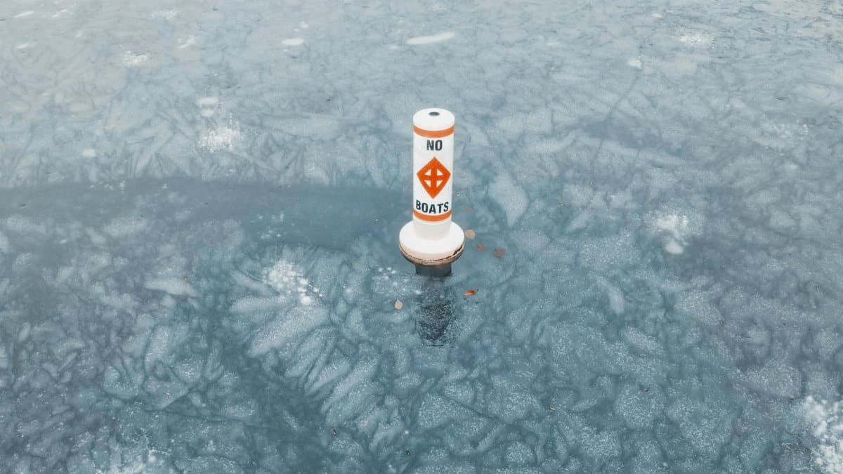 No boats warning buoy on a frozen lake symbolizes caution in icy conditions.