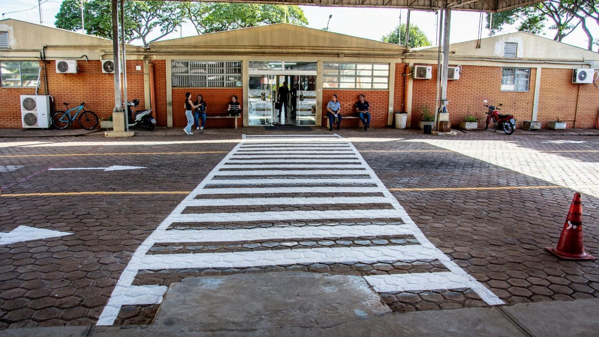 Busy pedestrian crossing at a facility entrance in Londrina, Brazil with people sitting and walking.