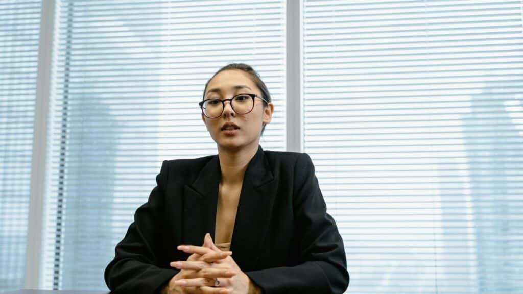 Confident businesswoman in formal attire during a meeting in a modern office setting.