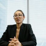 Confident businesswoman in formal attire during a meeting in a modern office setting.