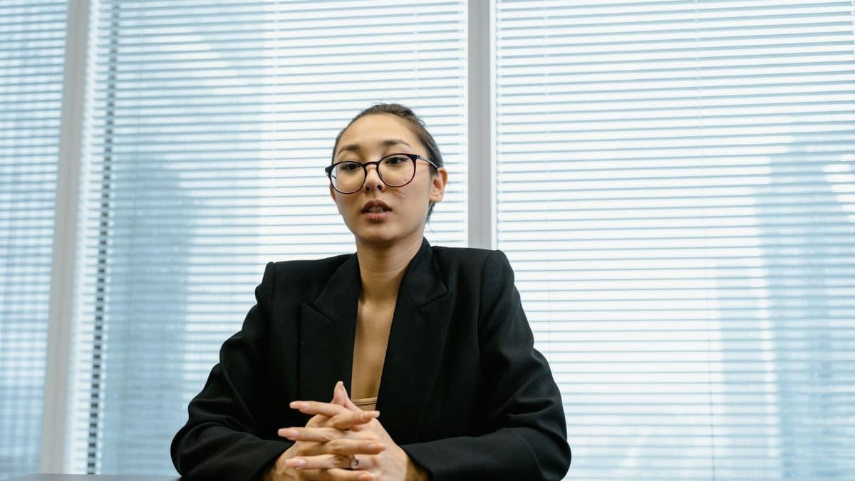 Confident businesswoman in formal attire during a meeting in a modern office setting.