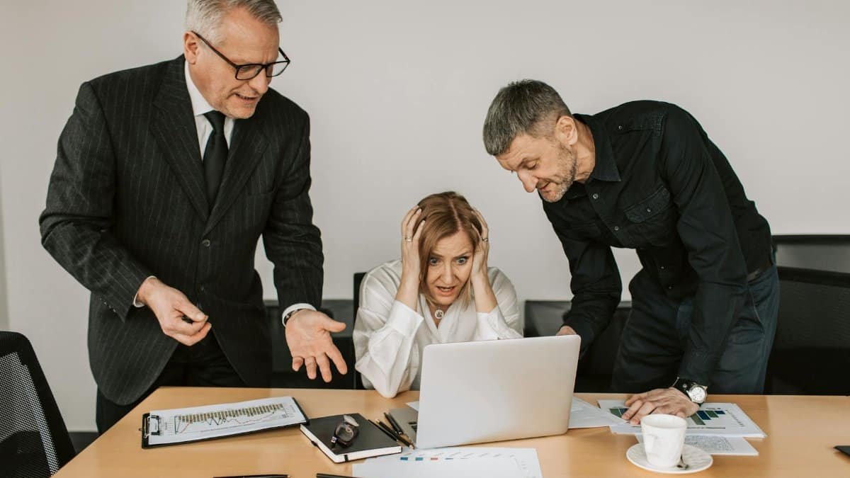 Three business professionals dealing with a stressful situation at work, highlighting workplace tensions.