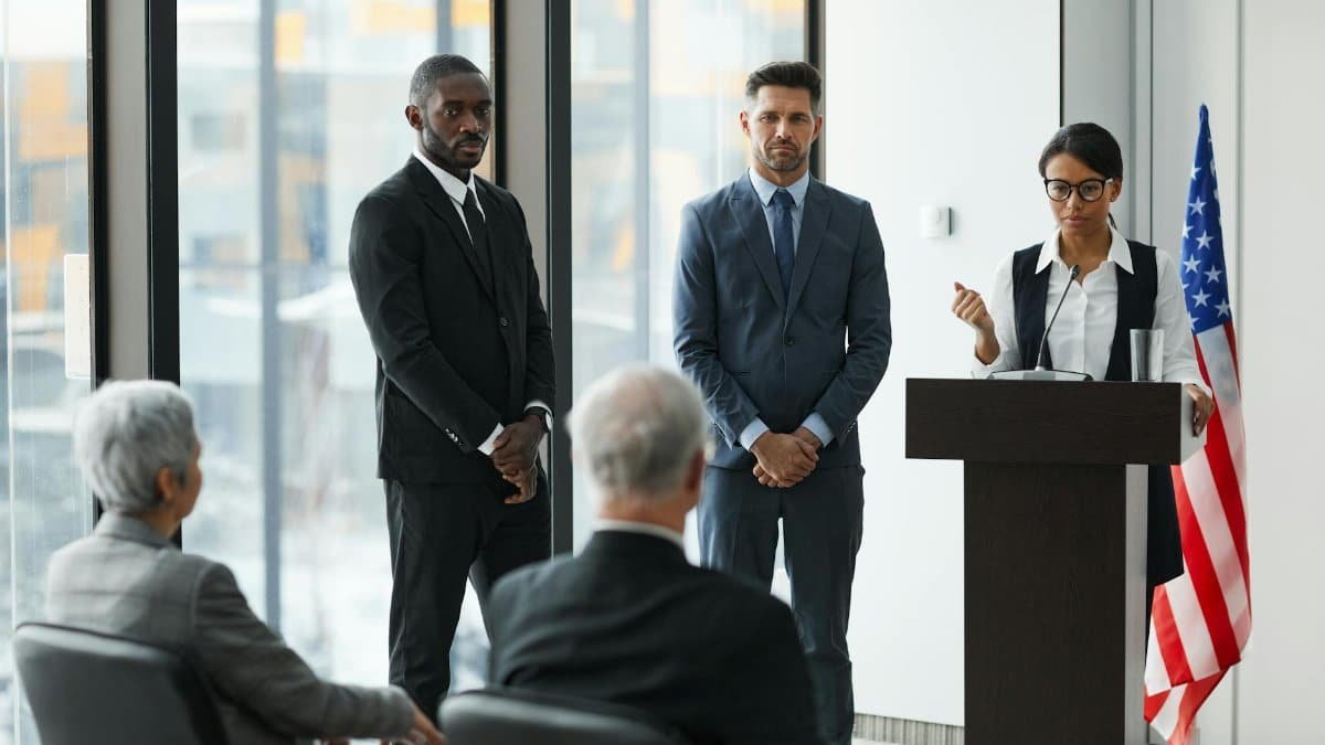 Professional speakers presenting at a conference in a modern room with glass windows.