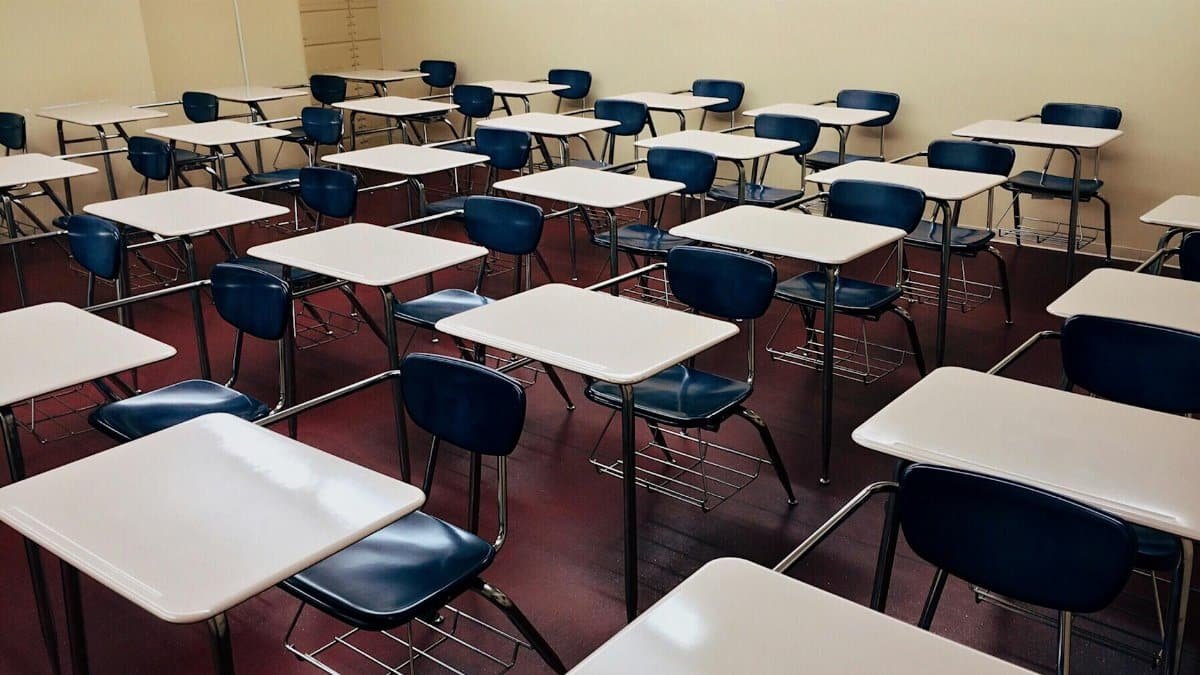 An indoor view of a modern, clean classroom with rows of empty desks and chairs.