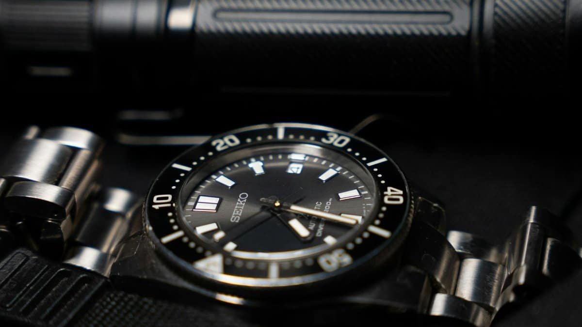 Close-up of a Seiko watch paired with a tactical flashlight in a sleek, stylish composition.
