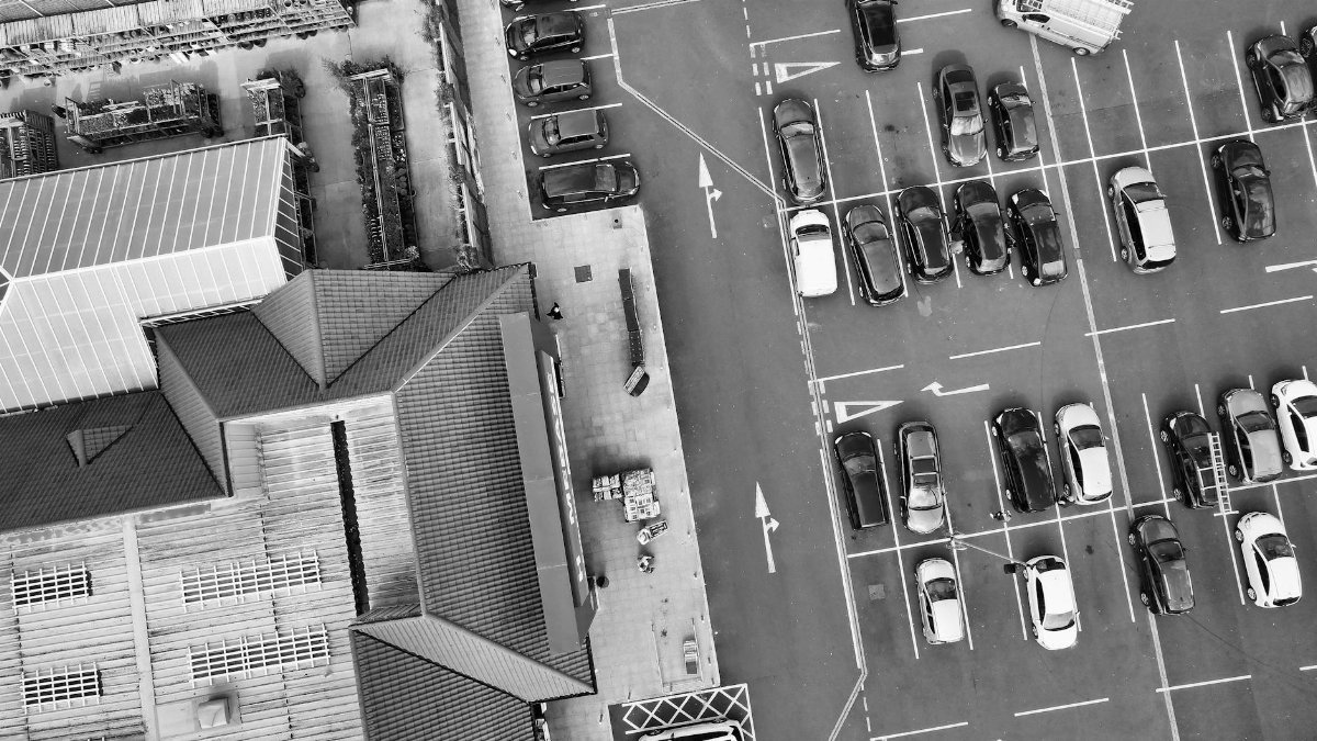 Black and white aerial view of a parking lot and buildings in England, showcasing urban life and architecture.