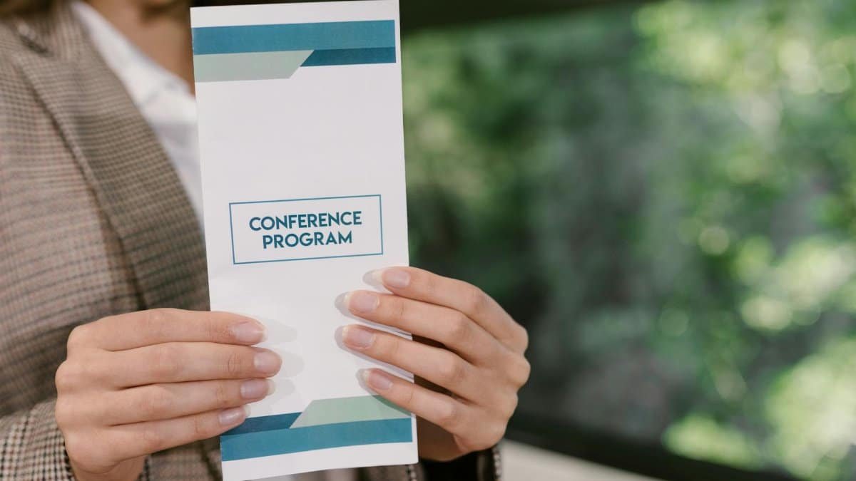 A professional holding a conference program brochure, ready for event attendees.