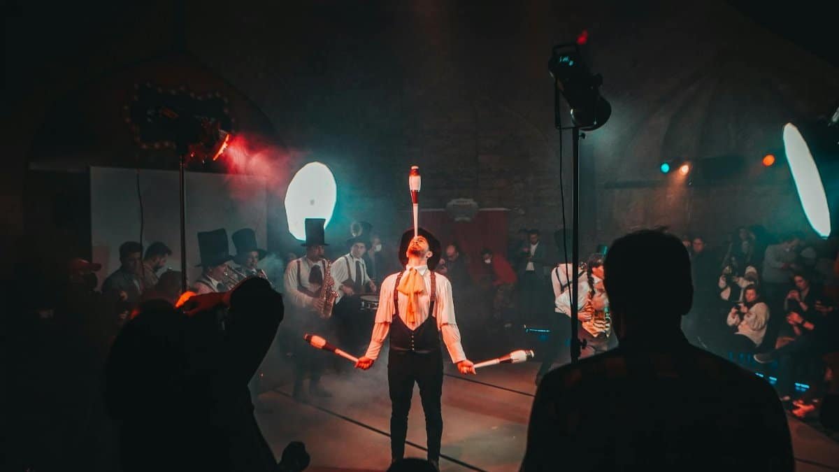 A mesmerizing circus juggler performs under dramatic lighting during a lively festival.