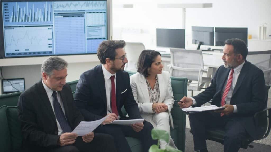 Group of business professionals discussing financial strategies in a modern office setting.
