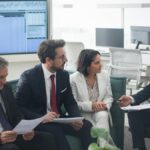 Group of business professionals discussing financial strategies in a modern office setting.