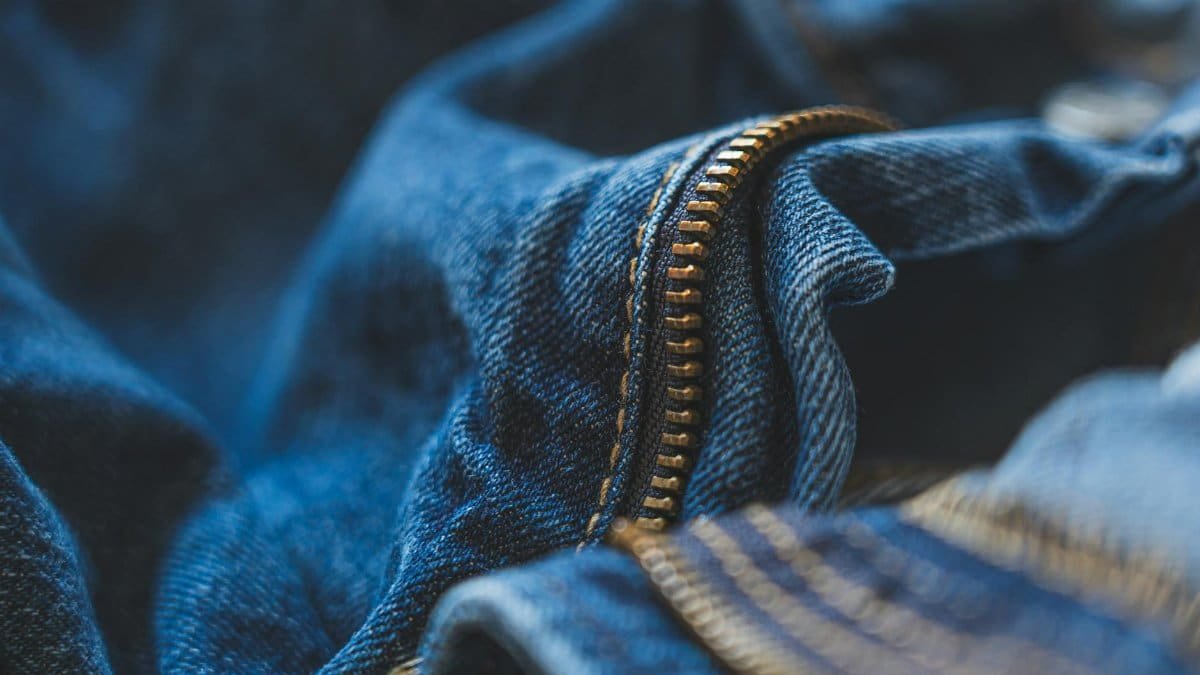 Detailed shot of blue denim fabric and zipper, highlighting texture and fashion element.