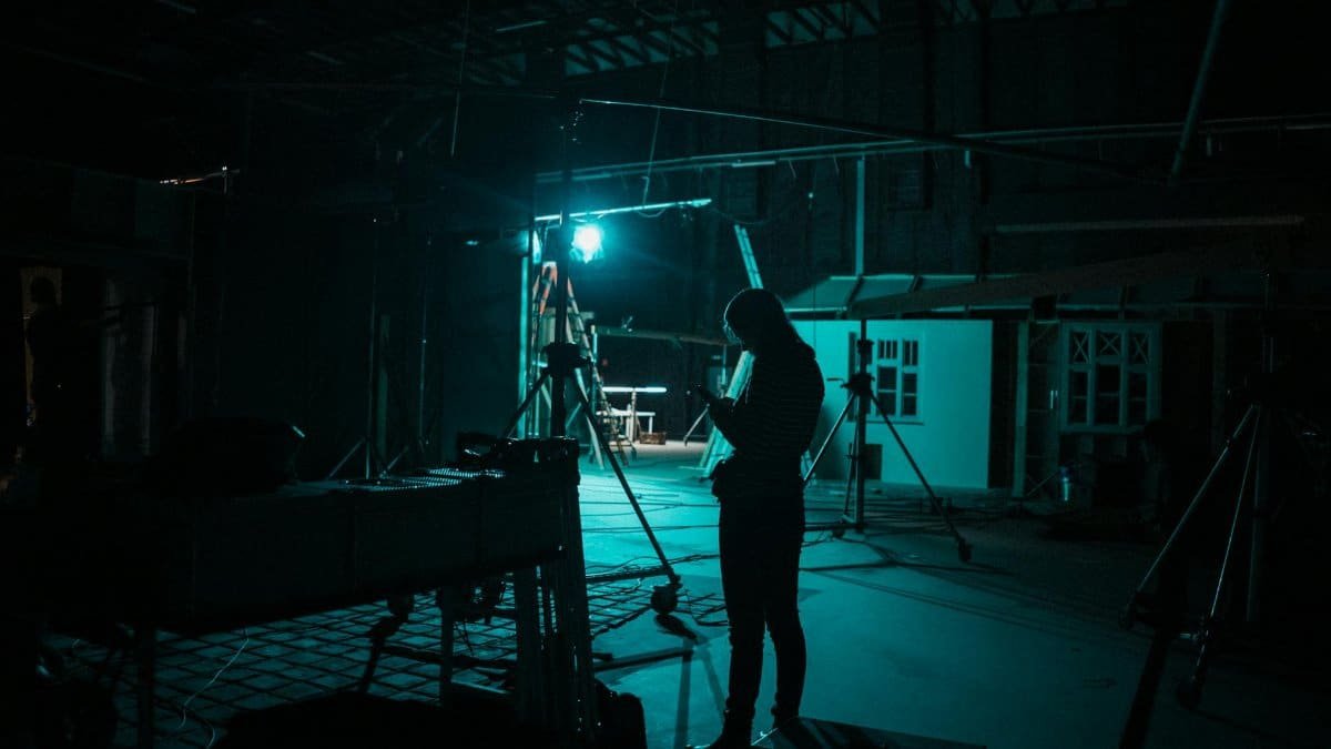 A silhouette of a woman on a dimly lit film set in Budapest creates a mysterious atmosphere.