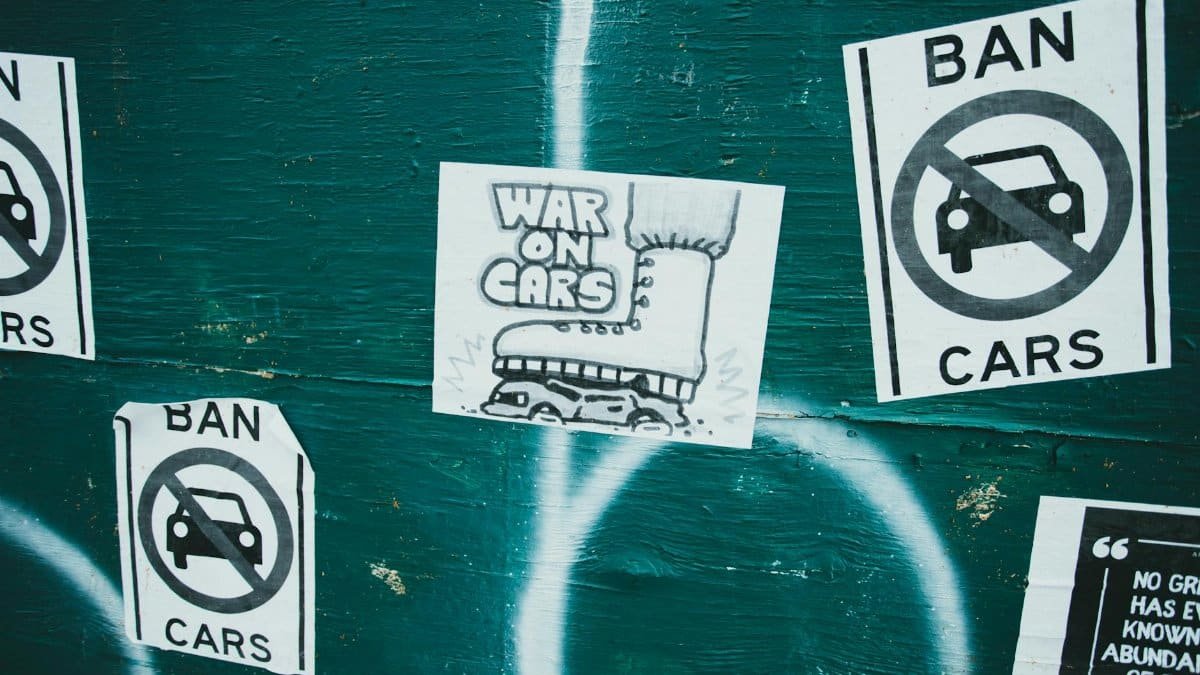 Posters advocating a car ban and promoting 'War on Cars' theme on an urban green wall.